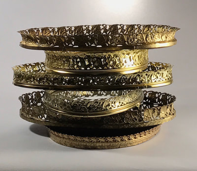 Stack of gold oval mirror trays for rent