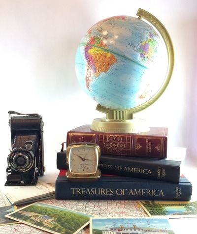 Travel themed centerpiece with a stack of vintage, Globe, antique camera, travel clock 