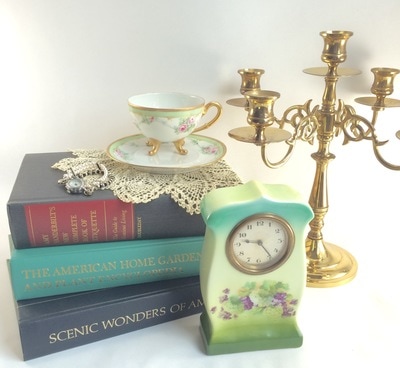 stack of books, teacup, candle holder and clock 