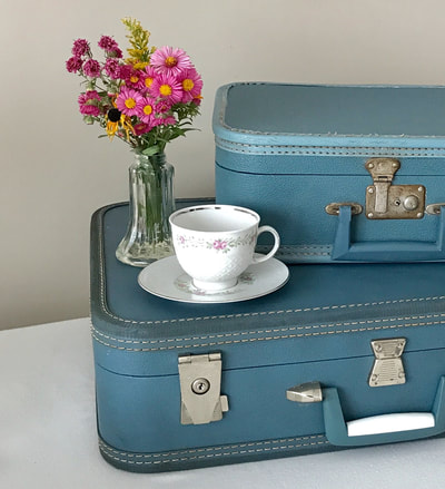 Stack of blue suitcases with a teacup