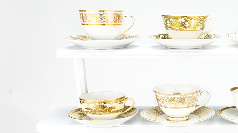 Glorious Gold teacups and saucer on a white wooden four-tiered stand
