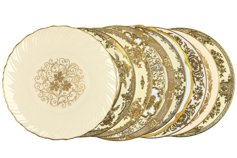 collection of our Gold and ivory dinner plates placed behind each other showing the mismatched gold embossed patterns of each plate.