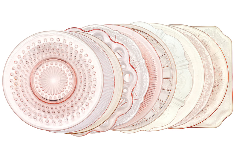 Vintage blush pink glass bread and butter plate rentals linen up in a row showing all of the edges of the different patterned pink plates.