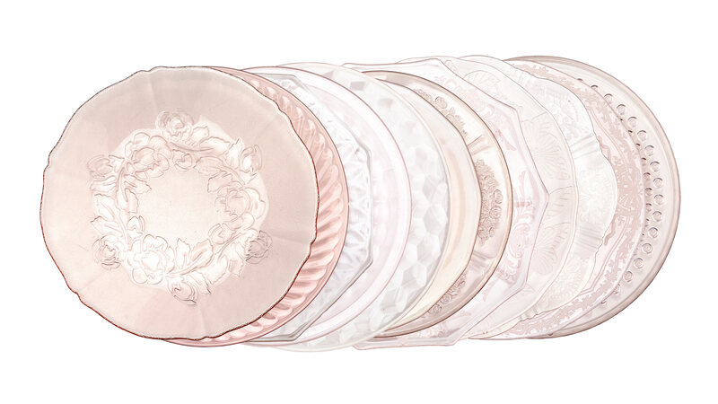 Vintage Pink glass plate rentals linen up in a row showing all of the edges of the different patterned blush pink plates.