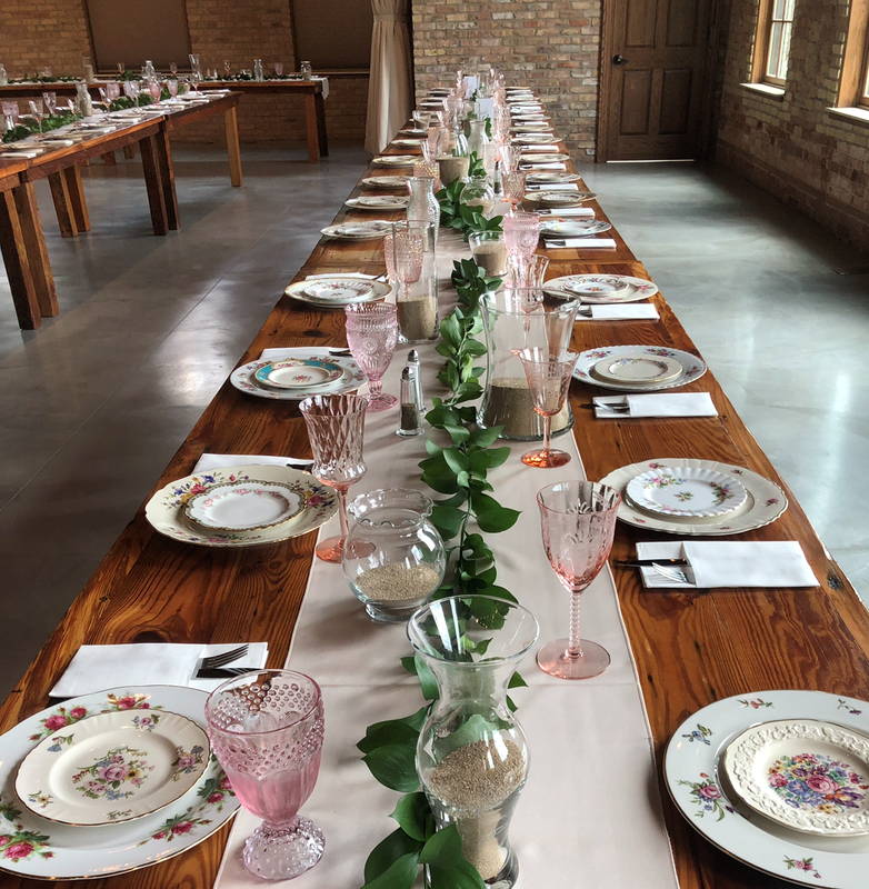 Elegant Floral Dishes, pink water goblets, stainless flatware on a farm table at the Brix in Carpentersville Illinois