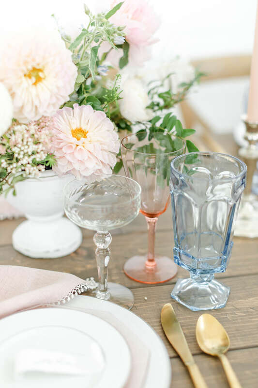 Peach Fuzz wine glass. Our vintage etched champagne coupe, Blush wine glass, and light blue water goblet with the blush florals and napkin, our brushed gold flatware and White Lace dinnerware are PERFECTION.