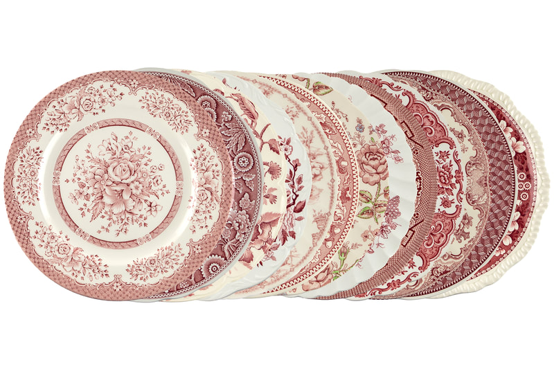 Vintage mismatched rose and white dishes in different patterns placed behind each other showing the different styles of each plate.